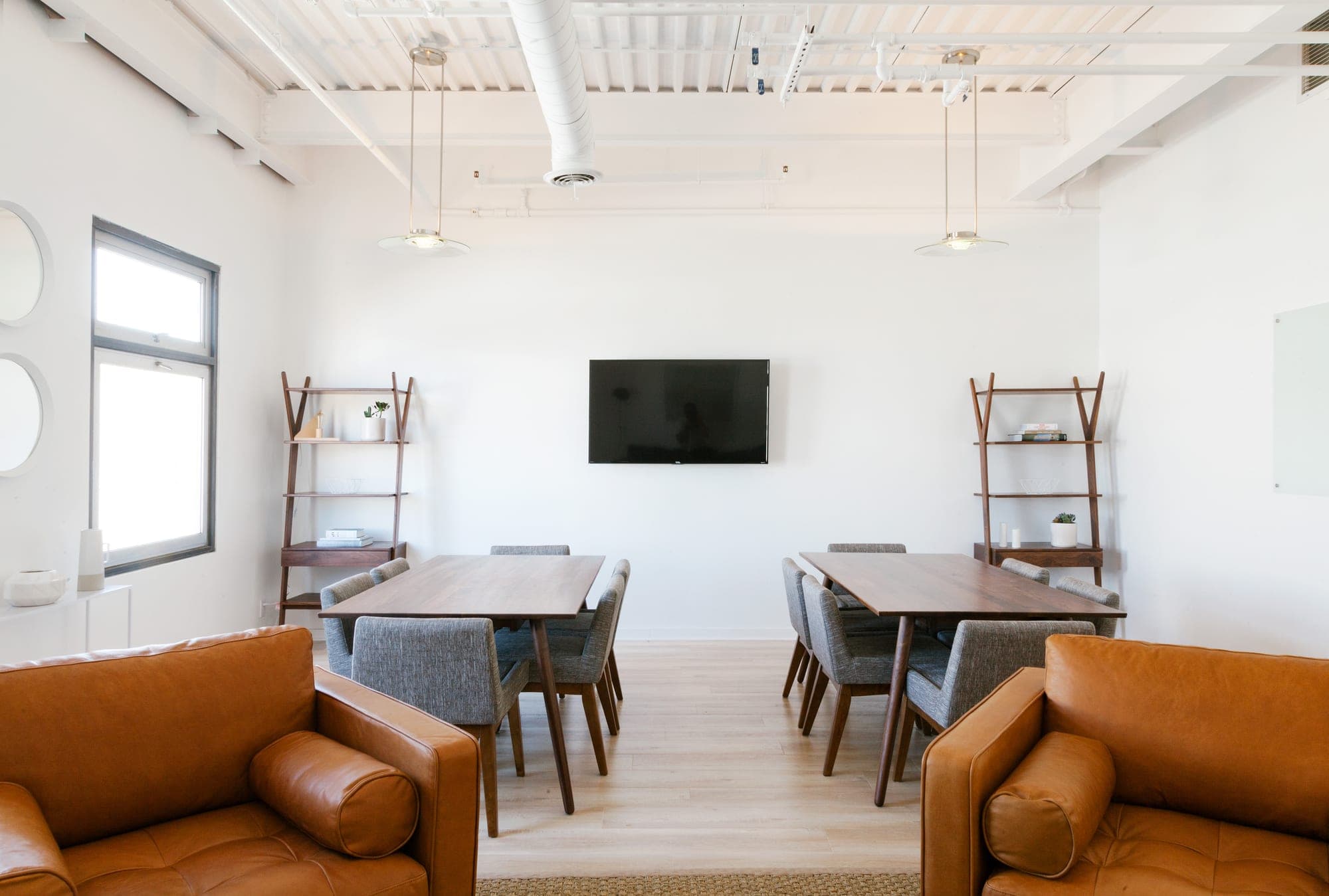 2 tan leather sofas facing a working table in a bright loft